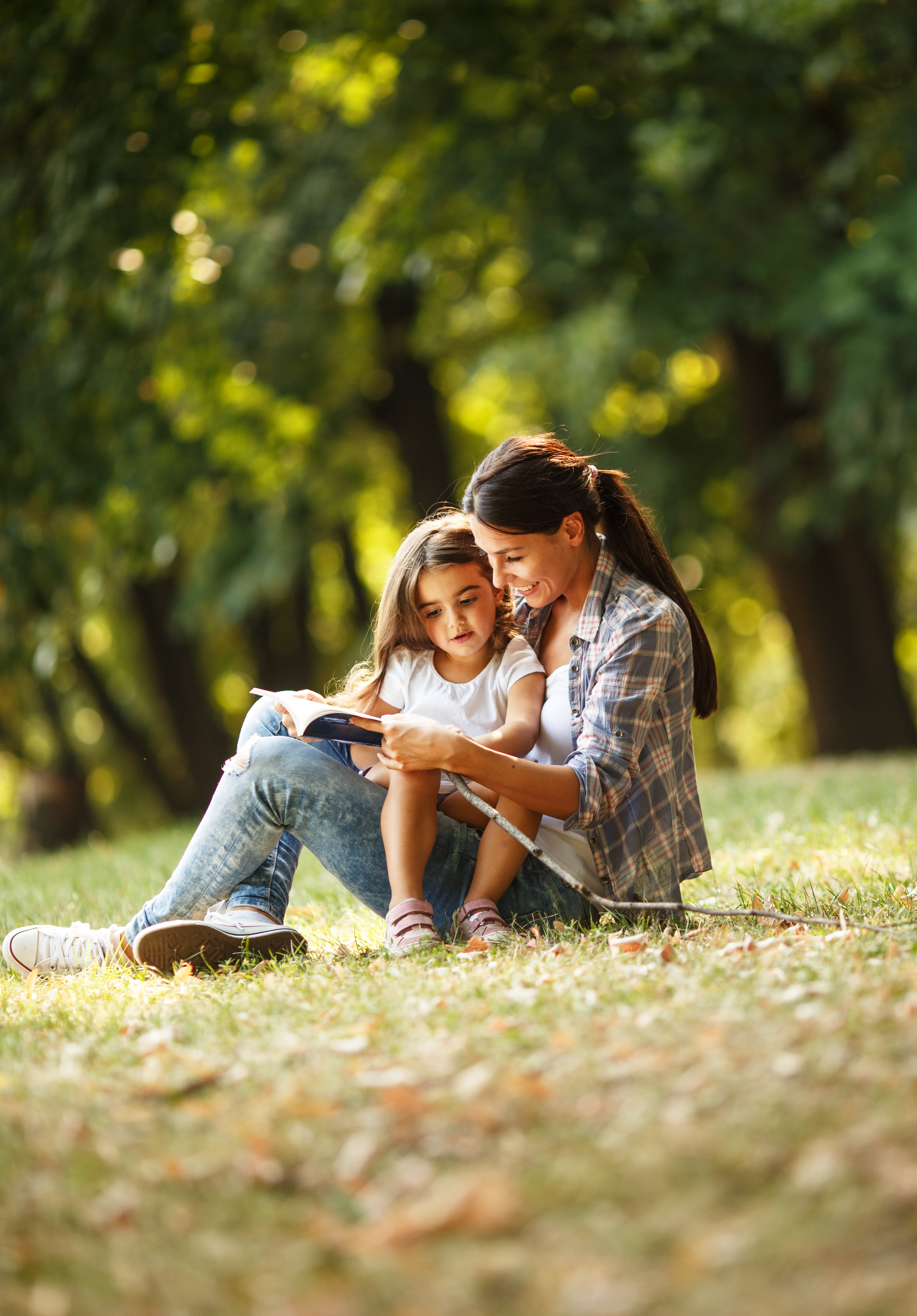 Mother and daughter relaxing in park.She reading a fairytale to her daughter